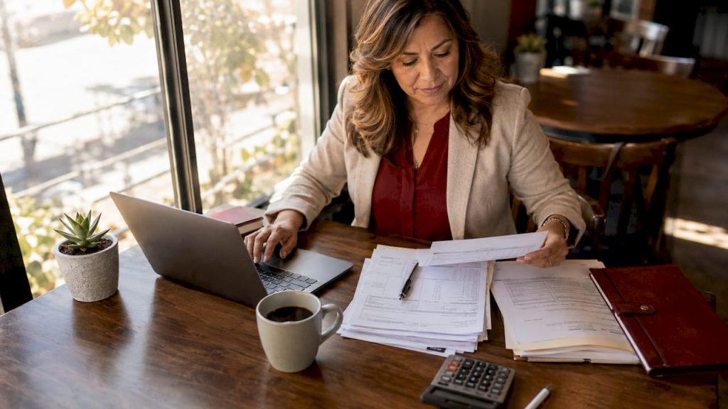 Small business owner reviewing payroll documents at desk