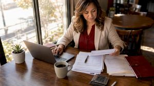 Small business owner reviewing payroll documents at desk