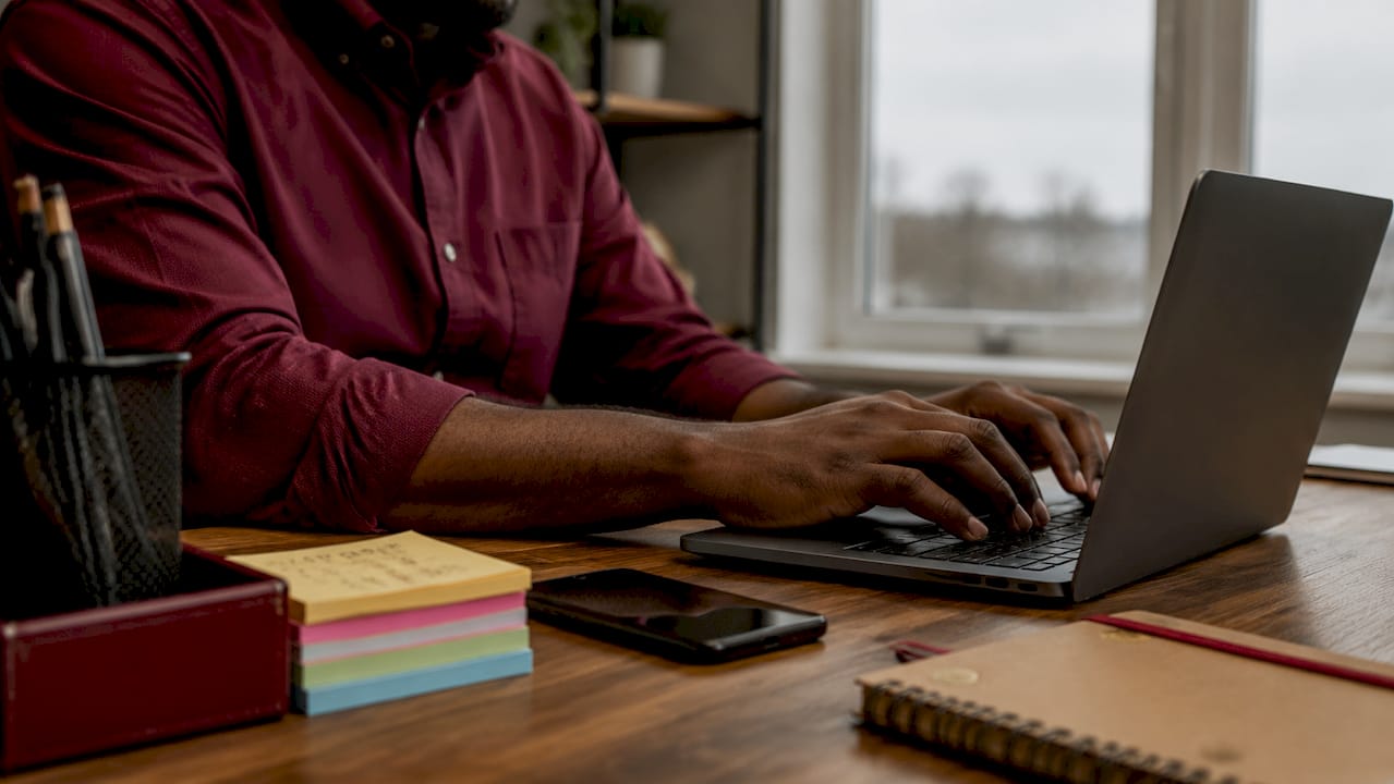 Hands typing on laptop in office setting