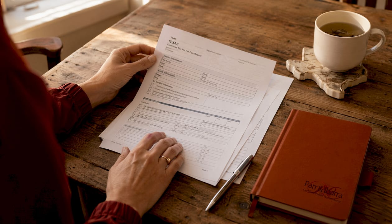 Hands holding Texas franchise tax forms on desk