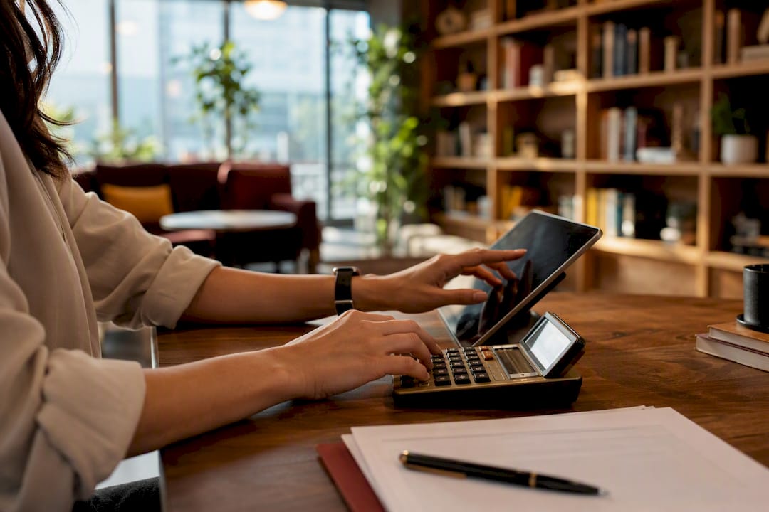 Hands calculating monthly sales tax in small office